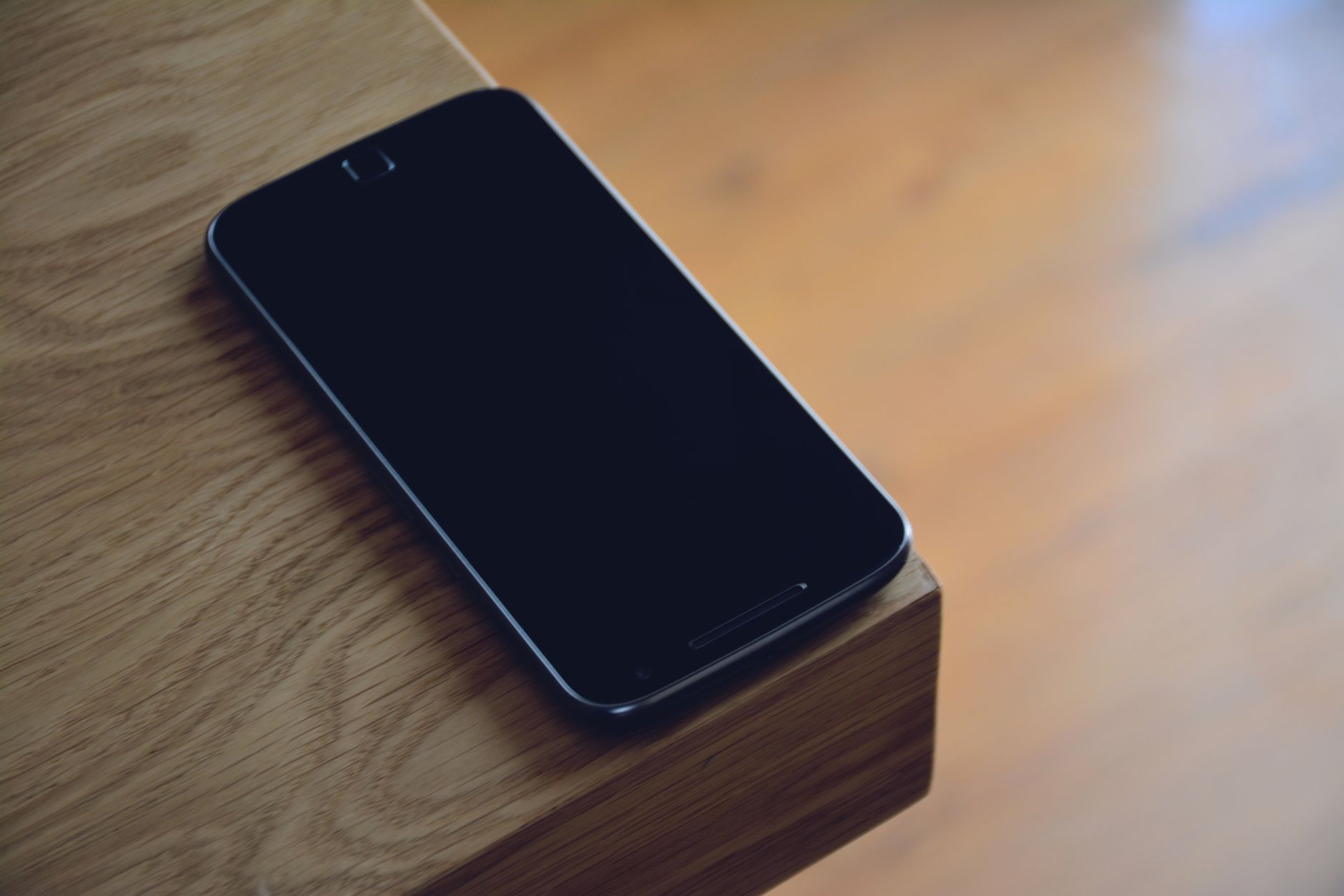 Older smartphones lined up on a wooden table